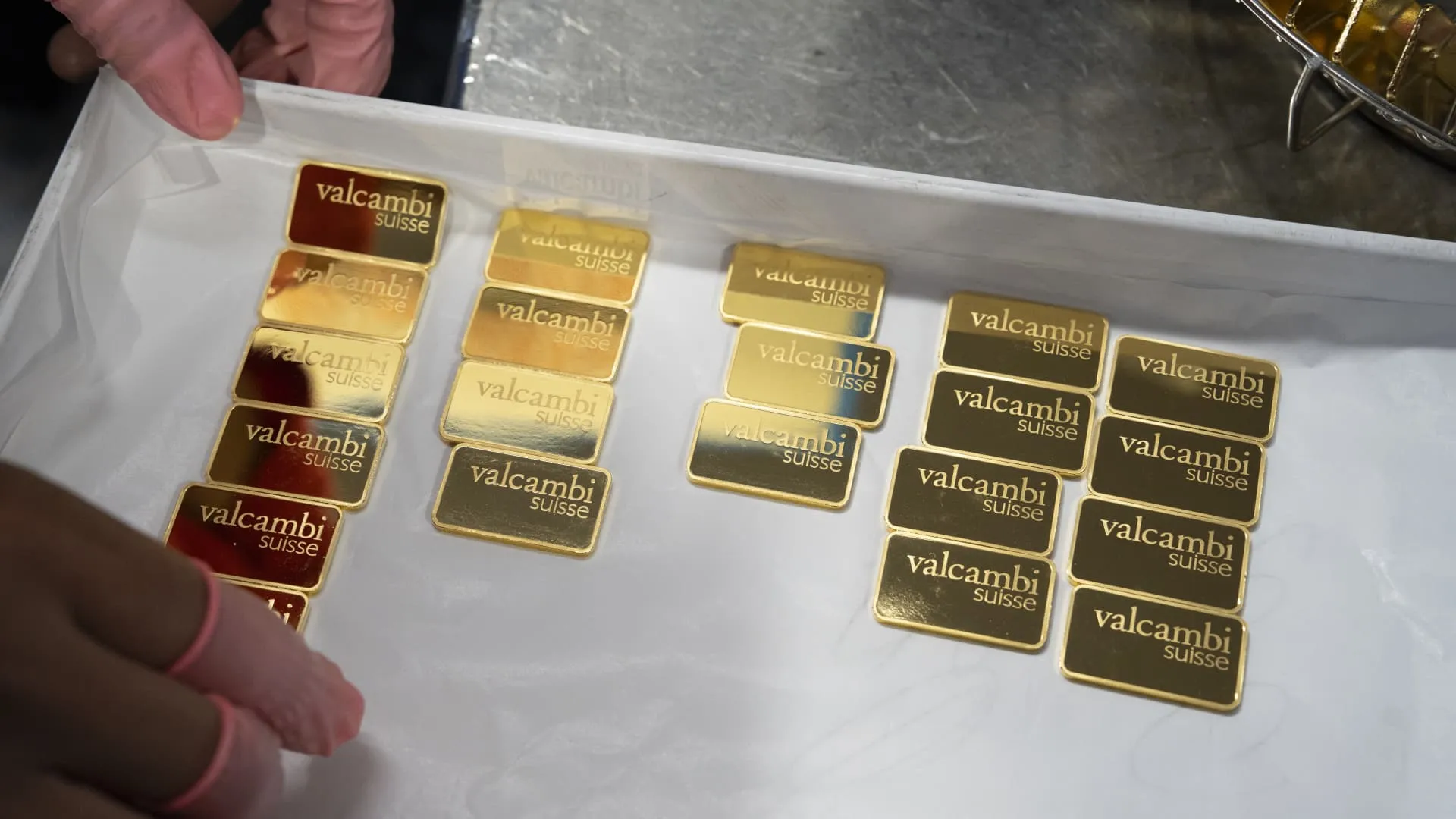 Gold bars stacked on table with financial charts in background